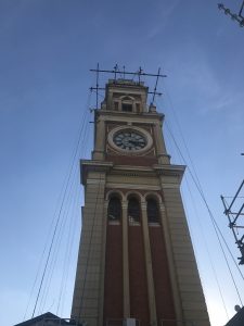 Foto da torre da Estação da Luz vista de baixo, envolta em cordas e estruturas que demonstram que ela está sendo restaurada.
