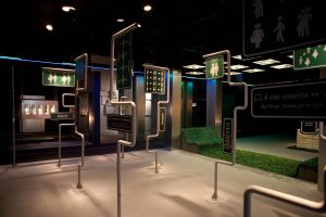 Foto de sala da exposição sobre a França onde há estruturas que simulam pontos de ônibus.