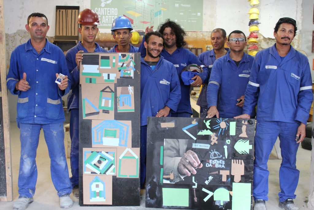 Foto de oito homens em pé durante a oficina Canteiro de Artes.