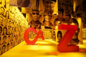 Foto da primeira sala da exposição Cazuza. A sala é amarela e há letras grandes vermelhas formando o nome do artista
